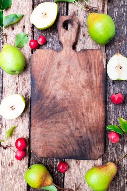 Pear and small apple around empty cutting board Premium Photo