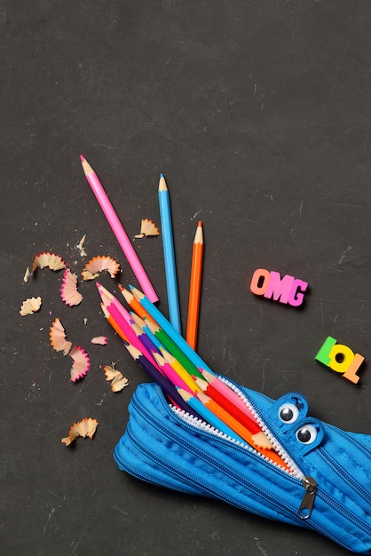 Premium Photo | Pencil case eating pencils on black chalk