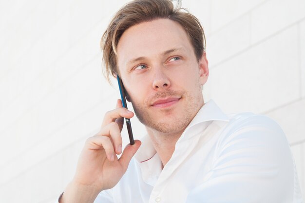 Pensive business man calling on smartphone outdoors Free Photo