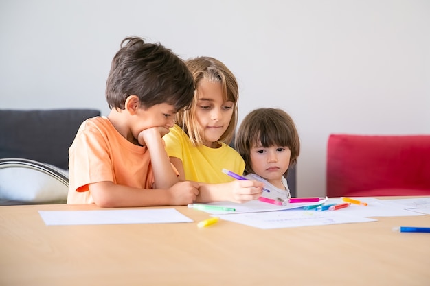 Free Photo Pensive Children Painting With Markers In Living Room Three Caucasian Adorable Kids Sitting Together Enjoying Life Drawing And Playing Together Childhood Creativity And Weekend Concept