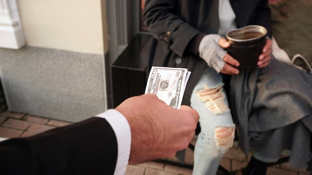 Premium Photo | People reach out with money, dollars to a homeless ...