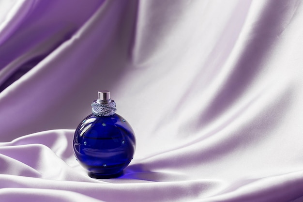 Premium Photo | Perfume bottle on lilac silk folded fabric. luxury ...