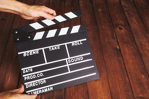 Free Photo | Person clapping clapperboard over wooden tabletop