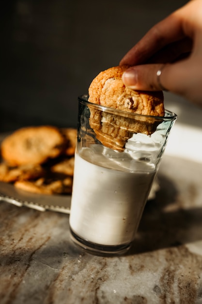 Free Photo | Person holding cookie dipping in milk