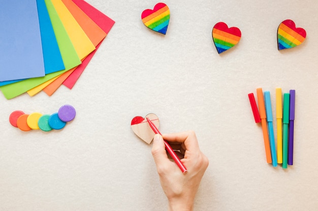Person painting rainbow heart with red felt pen Free Photo