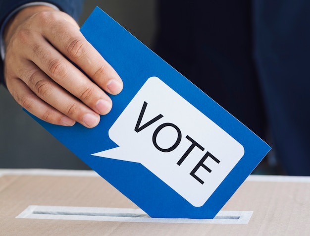 Person putting a ballot in an election box | Free Photo