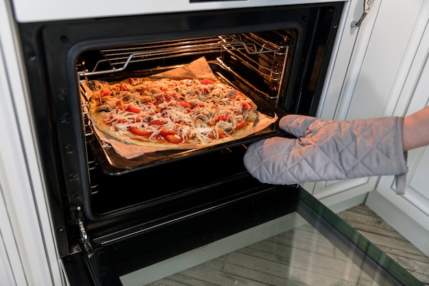 Person putting pizza in oven Photo | Free Download