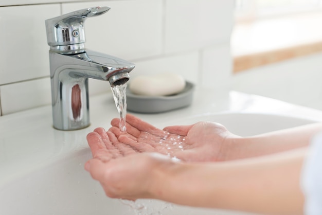 Premium Photo | Person rinsing their hands at the sink with water