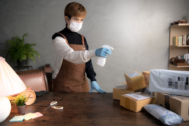 A person spraying disinfectant on parcels and boxes during coronavirus covid-19 pandemic Premium Photo