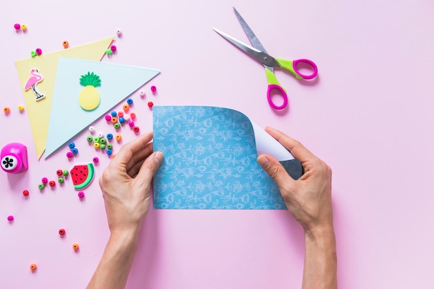 A Person Turning Blue Scrapbook Paper With Decorative Items On