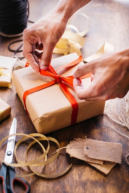 Person tying bow on gift box Free Photo