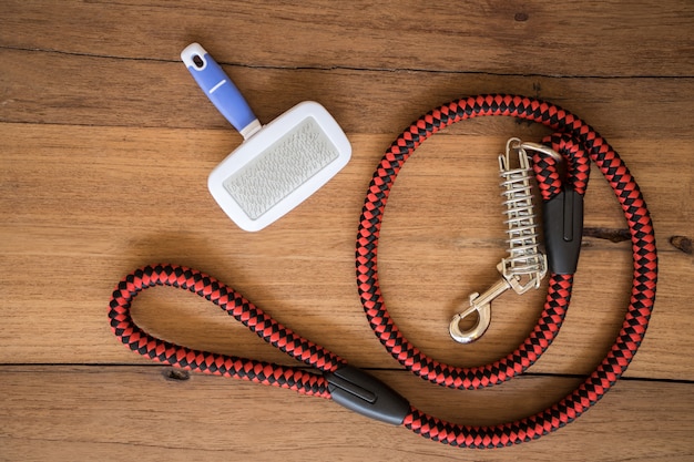 Pet leashes and brush on wooden background. Premium Photo