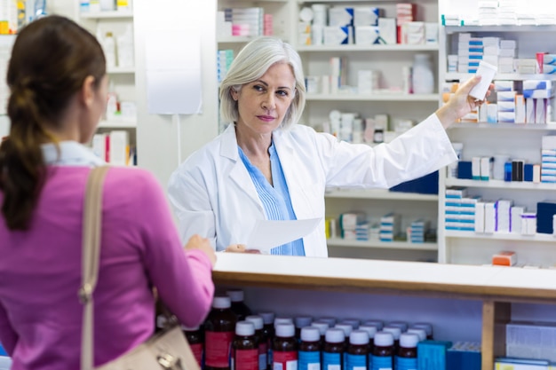 Premium Photo | Pharmacist showing the bottle of drug to customer