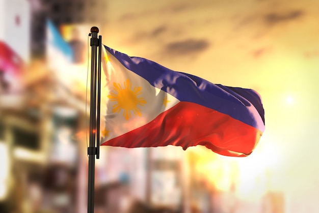 Philippines flag against city blurred background at sunrise backlight ...