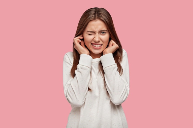 Free Photo | Photo of displeased woman plugs ears with discontent, doesnt want to hear annoying sound or noise