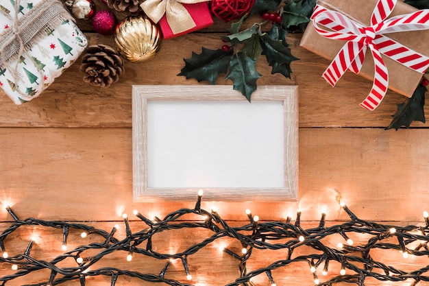 Free Photo | Photo frame between christmas decorations and illuminated fairy lights