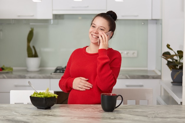 Premium Photo Photo Of Happy Laughing Brunette Woman Sitting In Kitchen And Speaking Via Smart