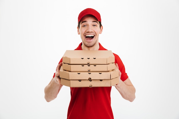 Download Photo of happy man from delivery service in red t-shirt and cap holding stack of pizza boxes ...