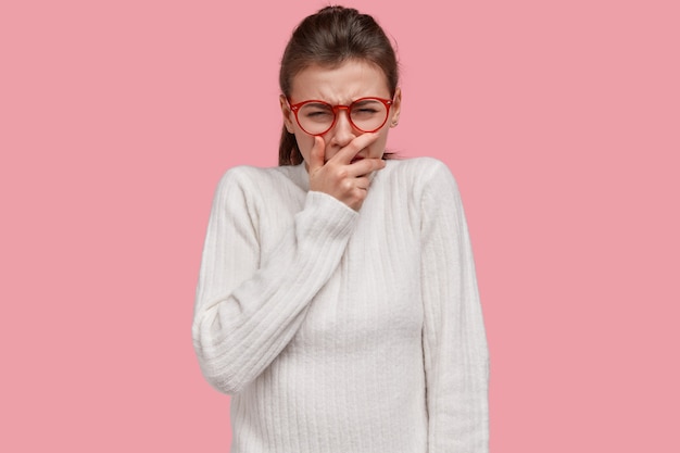 絶望的な女性の写真は絶望して泣き 人生に失敗し 口を覆い 否定的な感情を表現し カジュアルなセーターを着て ピンクのスタジオの壁をモデルにしています 人 無料の写真