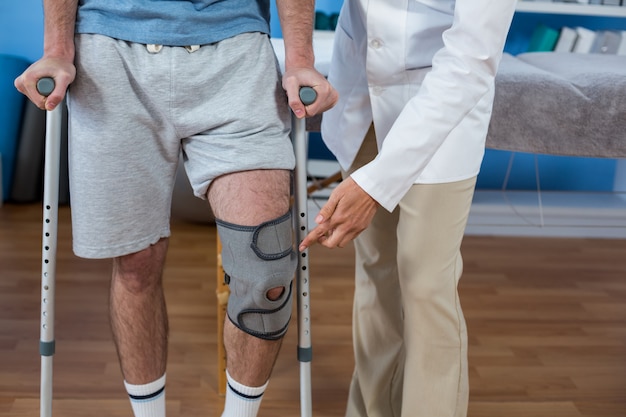 Premium Photo | Physiotherapist Helping Patient To Walk With Crutches