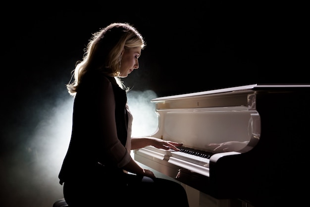 ピアニストのミュージシャンピアノ音楽演奏 女性パフォーマーと楽器のグランドピアノ プレミアム写真