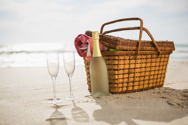 Picnic basket, champagne bottle and two glasses on sand Photo | Free ...