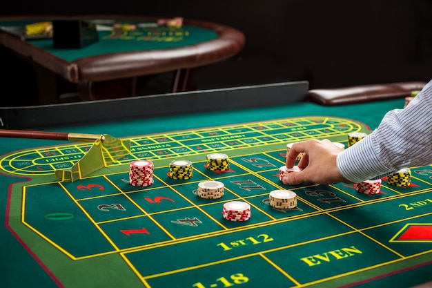 Premium Photo Picture Of A Green Table And Betting With Chips Man Hand Over Casino Chips On Roulette Table Close Up