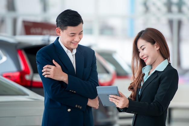 Pictures of asian customers and happy salespeople who buy new cars that enter into sales agreements with car dealers at car dealers. Premium Photo