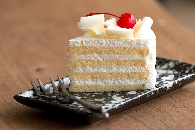 Premium Photo | Piece of white cake with vanilla frosting and cherry ...