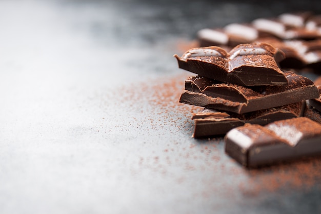 Pieces of chocolate on a wooden table and cacao sprinkled Free Photo