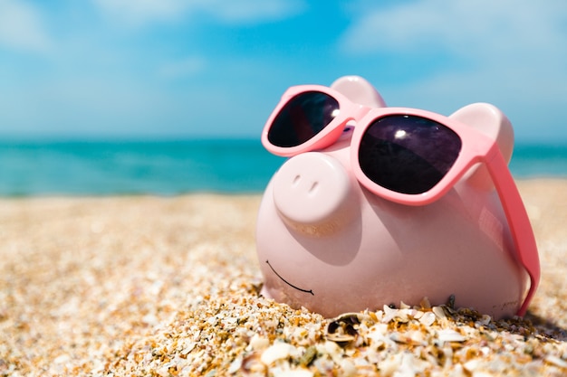 Premium Photo | Piggy bank wearing sunglasses relaxing at the beach
