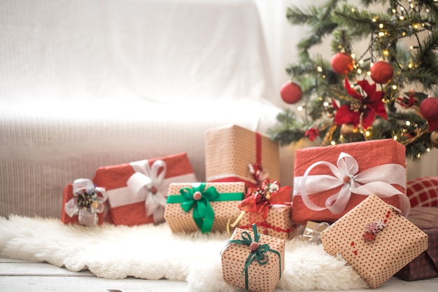 Pile of christmas presents over light wall on wooden table with cozy rug. christmas decorations Free Photo