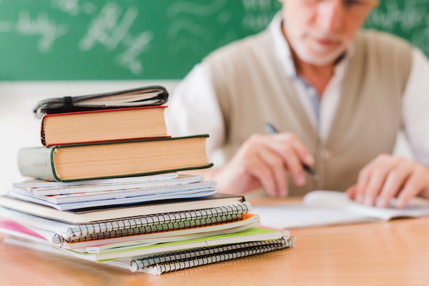 Pile of textbooks arranged on professor desk in lecture room Free Photo