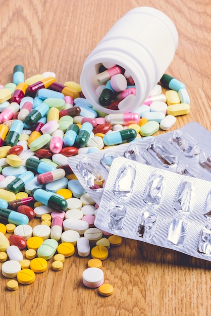 Premium Photo | Pill bottle spilling pills and empty blister pack on to ...