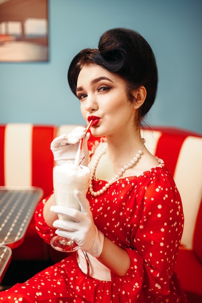 レトロなカフェ 人気のアメリカンファッション50年代と60年代のストローでメイクアップドリンクミルクセーキで女の子をピンで留めます プレミアム写真