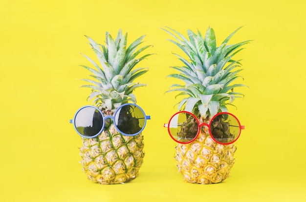 プレミアム写真 黄色の背景に赤と青のサングラスとパイナップル