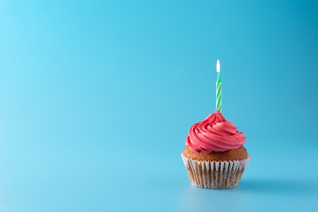 Premium Photo | Pink birthday cupcake with green candle on blue background