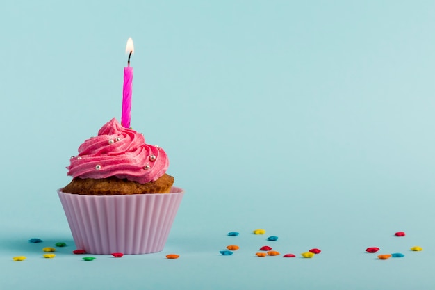 Pink Burning Candles On Decorative Muffins With Colorful Star Sprinkles 