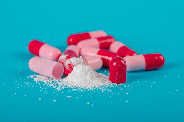 Premium Photo | Pink capsule pills on blue background. antibiotics