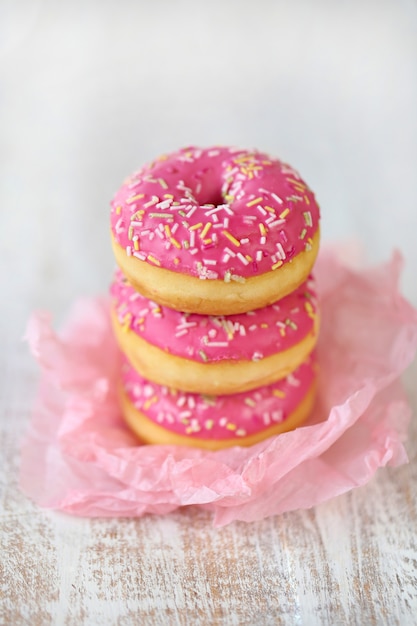 Pink donut in a pile on a light wooden Premium Photo