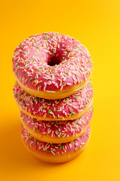 Premium Photo | Pink donuts on yellow background top view