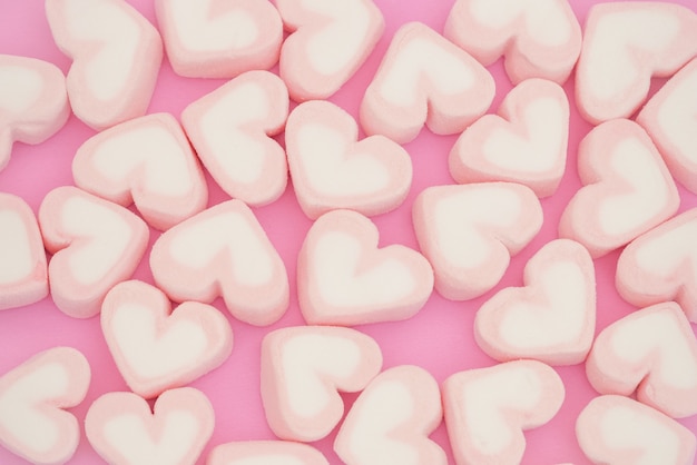 ピンクのマシュマロ ピンクの背景にマシュマロのお菓子の心を聞く プレミアム写真