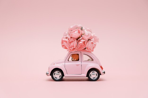 Pink retro toy car delivering bouquet of flowers | Premium Photo
