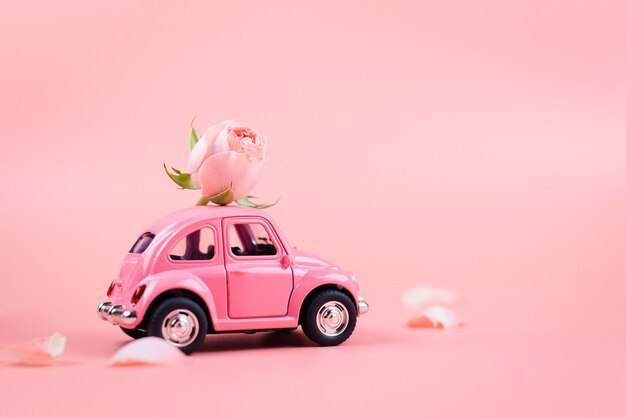 ピンクのレトロなおもちゃの車は ピンクの背景にピンクの花を届けます 2月14日のはがき バレンタインの日 3月8日 国際女性の日 プレミアム写真