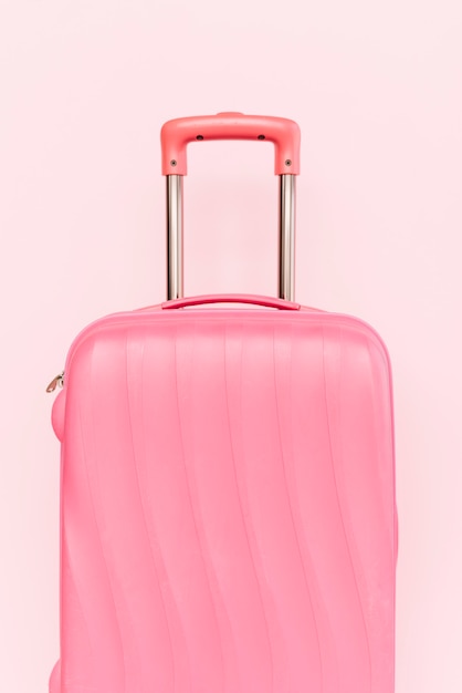 Pink suitcase for travelling against pink background | Free Photo