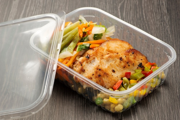 Premium Photo | Plastic lunch box with grilled chicken fillet and ...