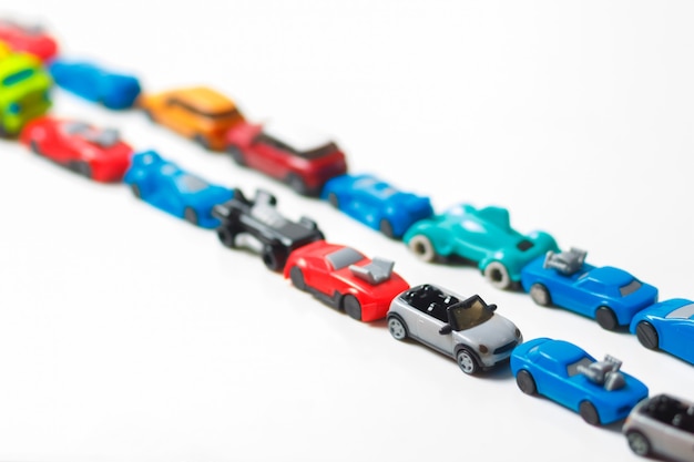 Plastic multi-colored toy cars are lined up on white | Premium Photo