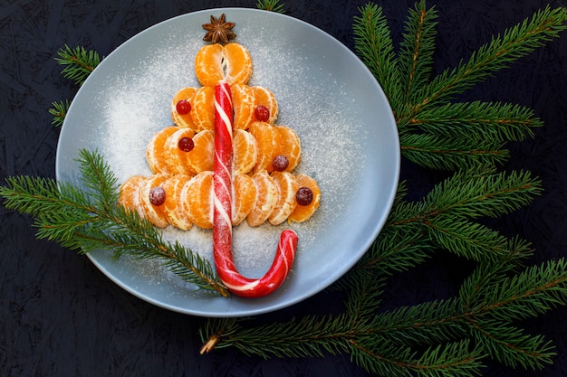 A plate with mandarin slices laid. black background. view from above. new year's and chris Premium Photo