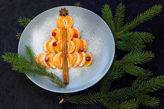 A plate with mandarin slices laid. black background. view from above. new year's and chris Premium Photo