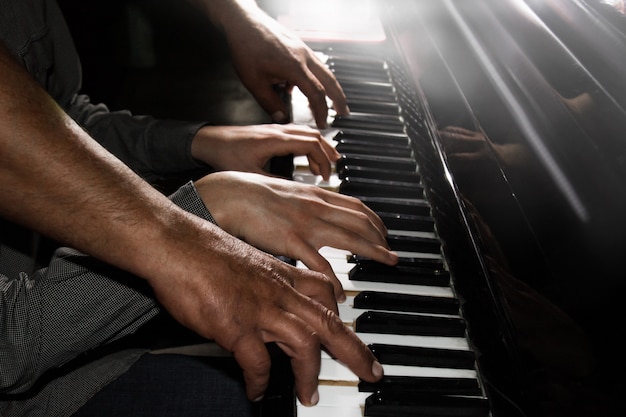 Premium Photo | Playing four male hands on the piano. palms lie on the